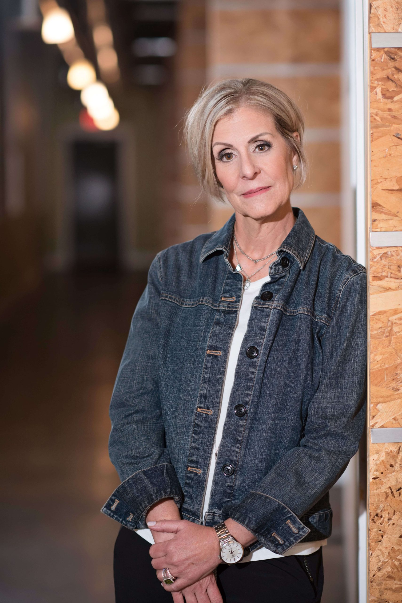 Kim Boudreau Smith standing next to a brick wall, hands crossed in the fron of her body